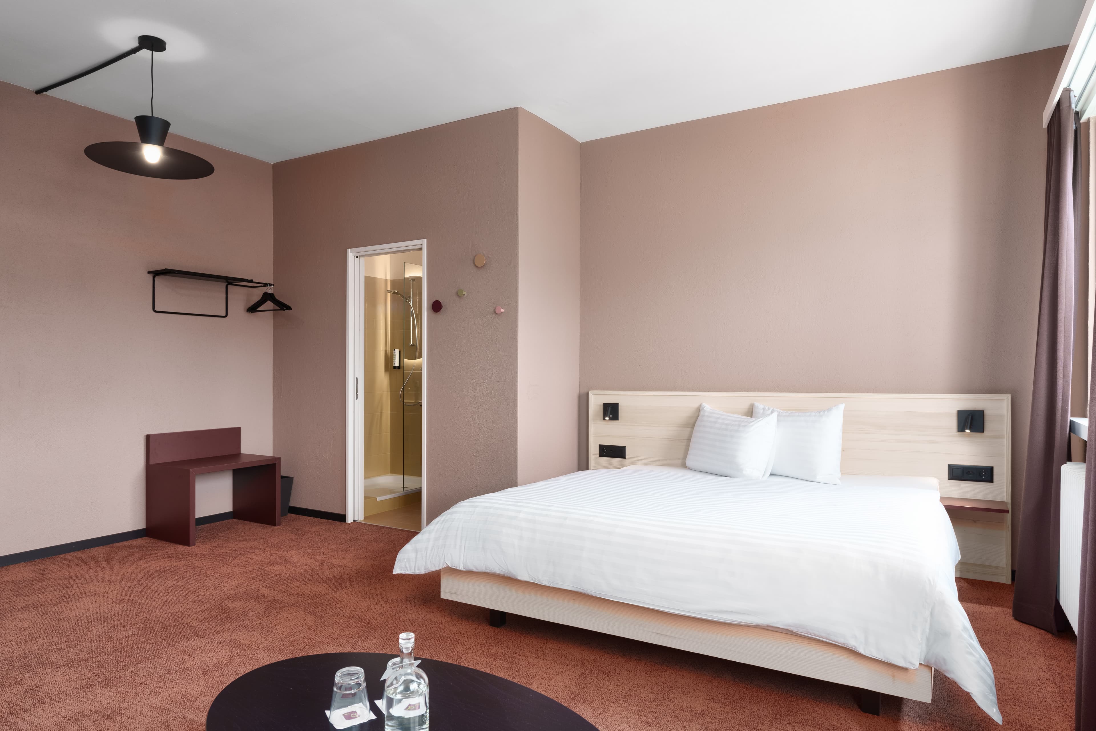 A modern double room in the monastery by b smart with a bright double bed an open wardrobe and a small table with water glasses